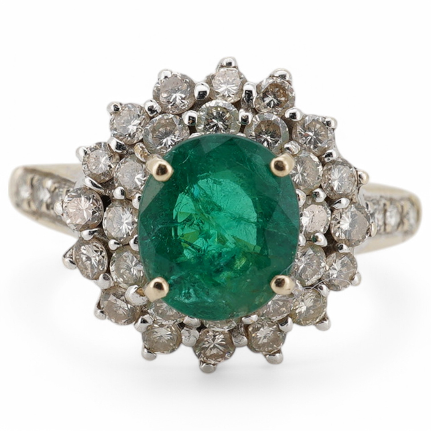 A modern 18ct, emerald and diamond set oval cluster ring with diamond set shoulders, size N/O, gross weight 4.1 grams. Condition - poor to fair